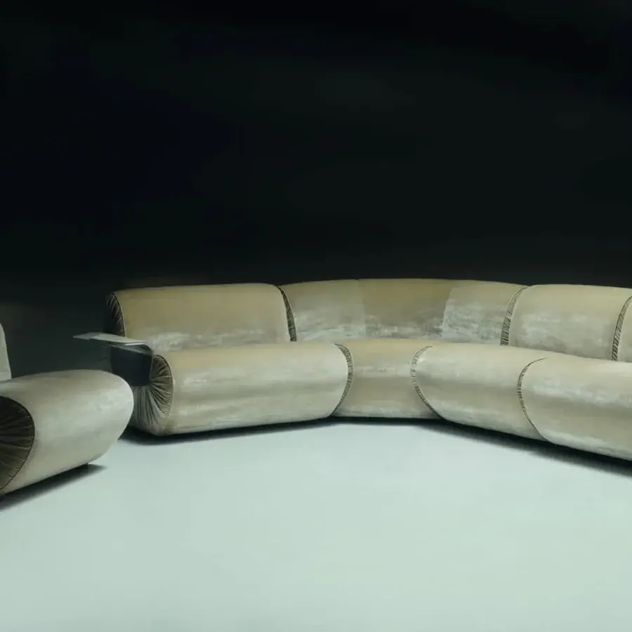 Luxury Visionnaire Joker sectional with satin‑finish muted gold‑beige textile, pleated, wing‑shaped leather‑padded metal armrest, discreet metal inserts