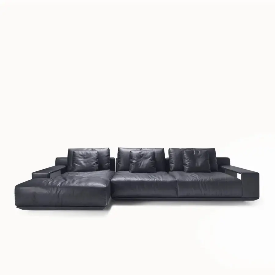 Elegant sectional with dark charcoal gray leather, slightly glossy, L‑shaped silhouette, metal armrests, brutalist‑inspired block and void arrangement