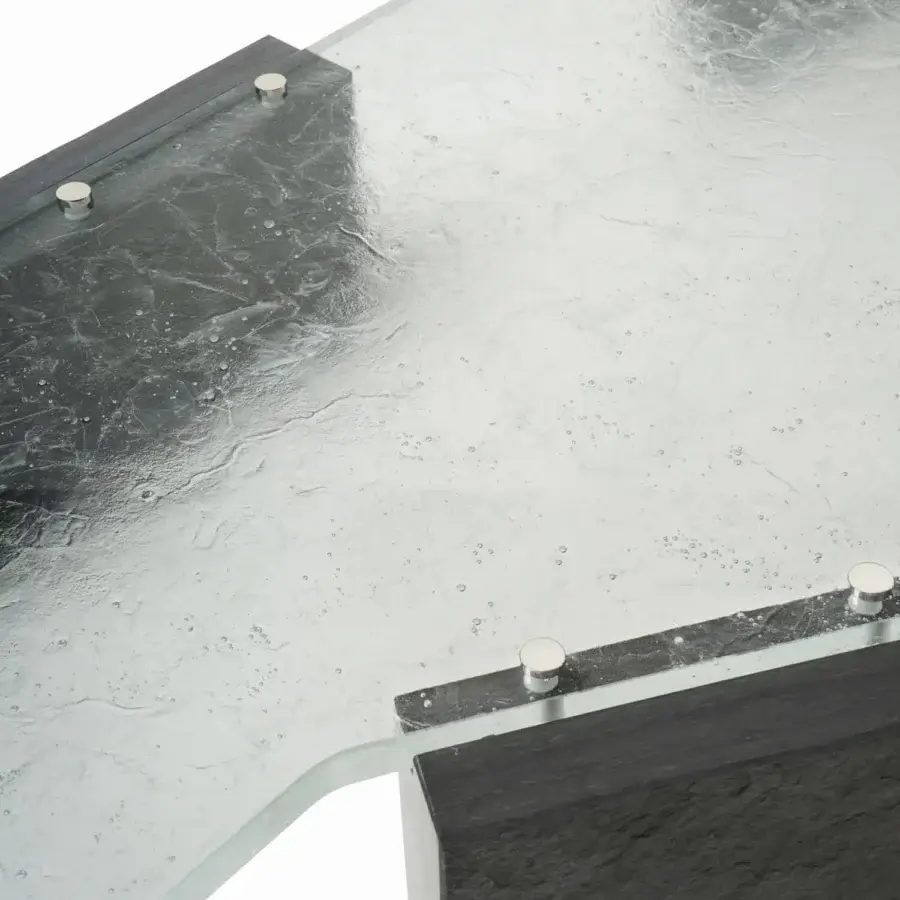 Luxury Visionnaire Stealth coffee table with thick angular glass panel shimmering silvery internal fractures and matte dark Moltrasio stone base with palladium brass studs