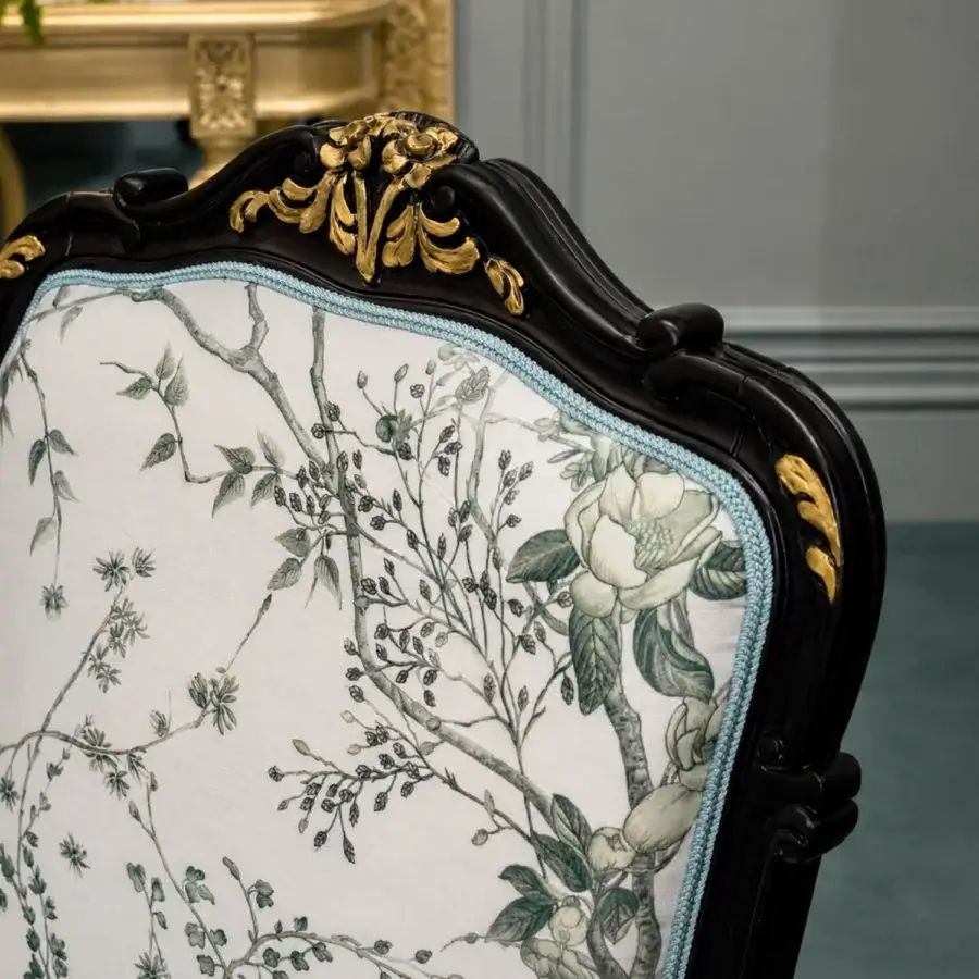 Distinctive Bellotti Ezio dining chair with black lacquered tempera brush finish, aged gold accents, cream upholstered backrest botanical print muted green grey, light blue braided trim, carved foliate silhouette