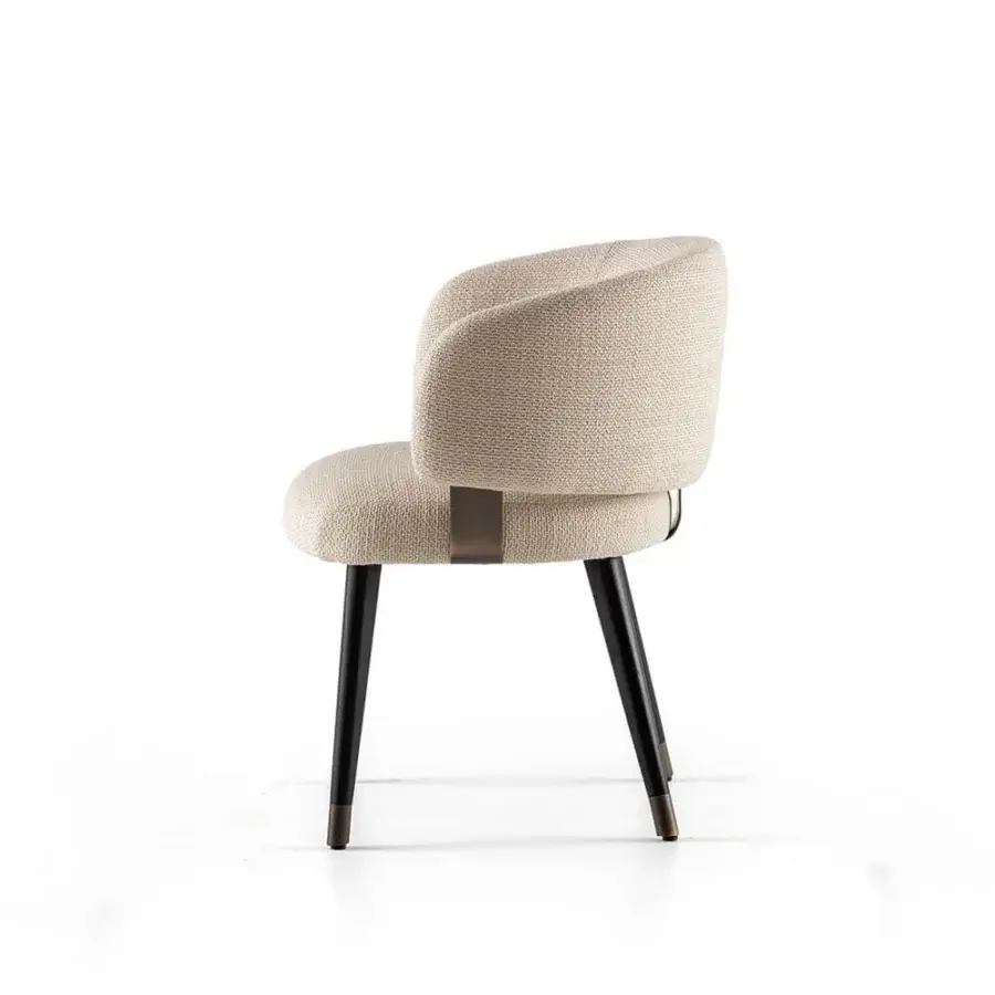 Luxury armchair upholstered in muted beige‑cream textile with tapered wood legs dark matte finish and bronze‑toned metal accents