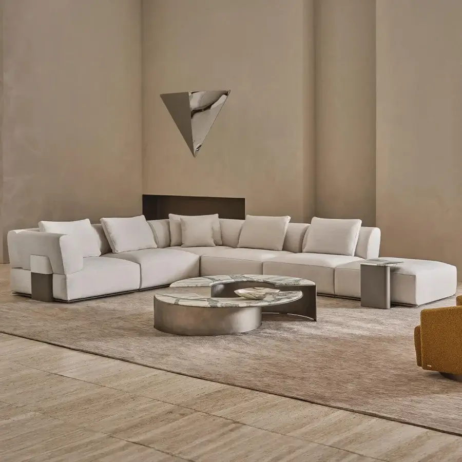 Contemporary Rugiano Hatton sectional with low-profile, off-white textile upholstery, leather-wrapped base, marble side tables