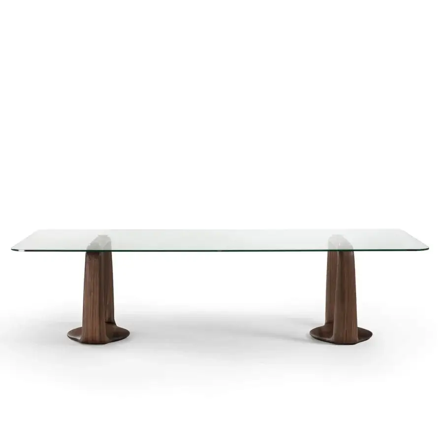 棋Refined Porada Saddle Glass Table with clear surface supported by canaletta walnut legs that curve and widen at base