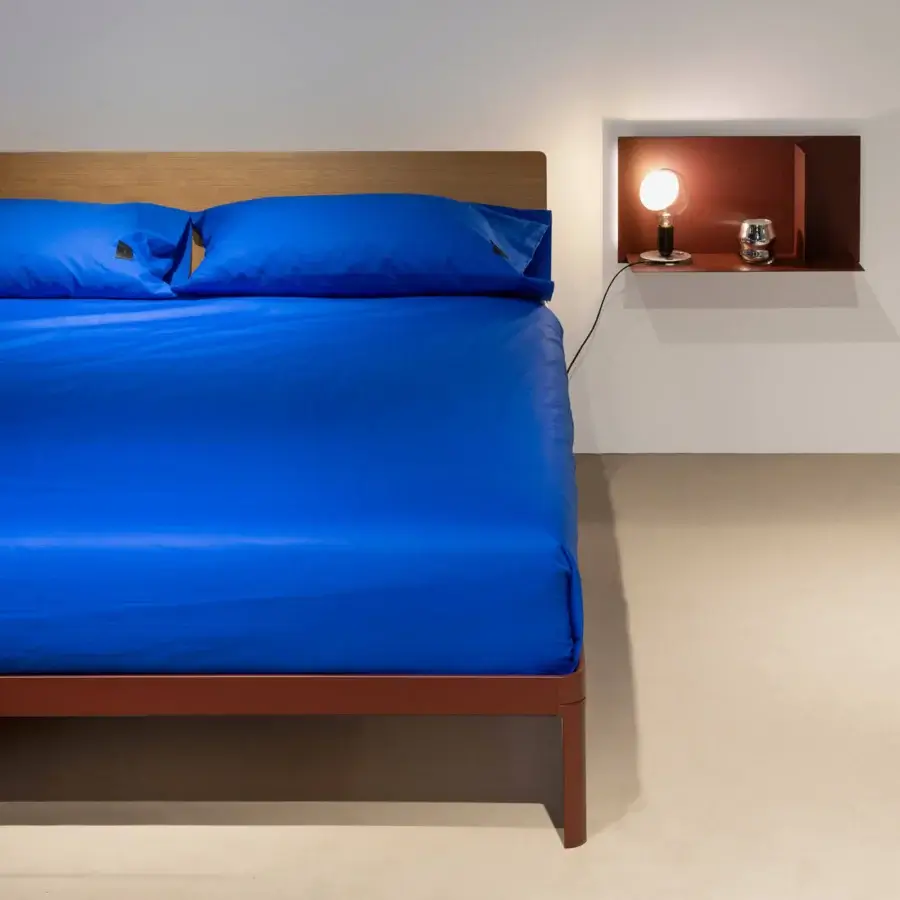Elegant Kristalia AluAlu Bed with natural‑grain wood headboard, Argilla‑finished metal frame and royal‑blue textiles