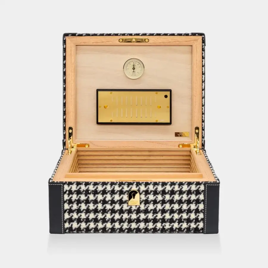 Sophisticated Vèlle Milano Cigars humidor in black and white houndstooth fabric with leather trims alongside gold-toned metal