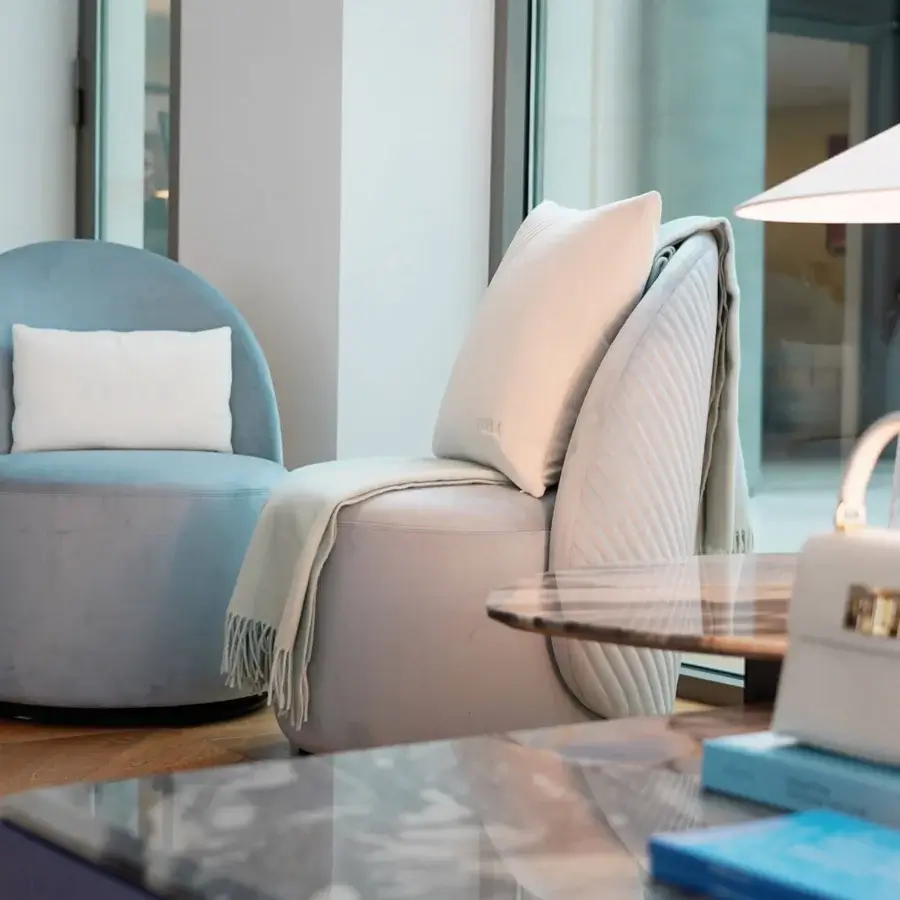 Sophisticated Furla Casa Venus swivel lounge chair in muted pastel blue textile with quilted V detail and matte black base