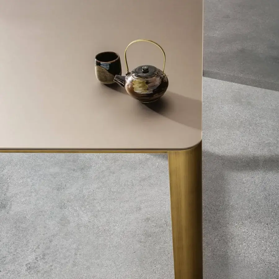 Exclusive Sovet Italia Kodo table with cylindrical legs in a brushed, brass-like tone and muted beige ceramic top