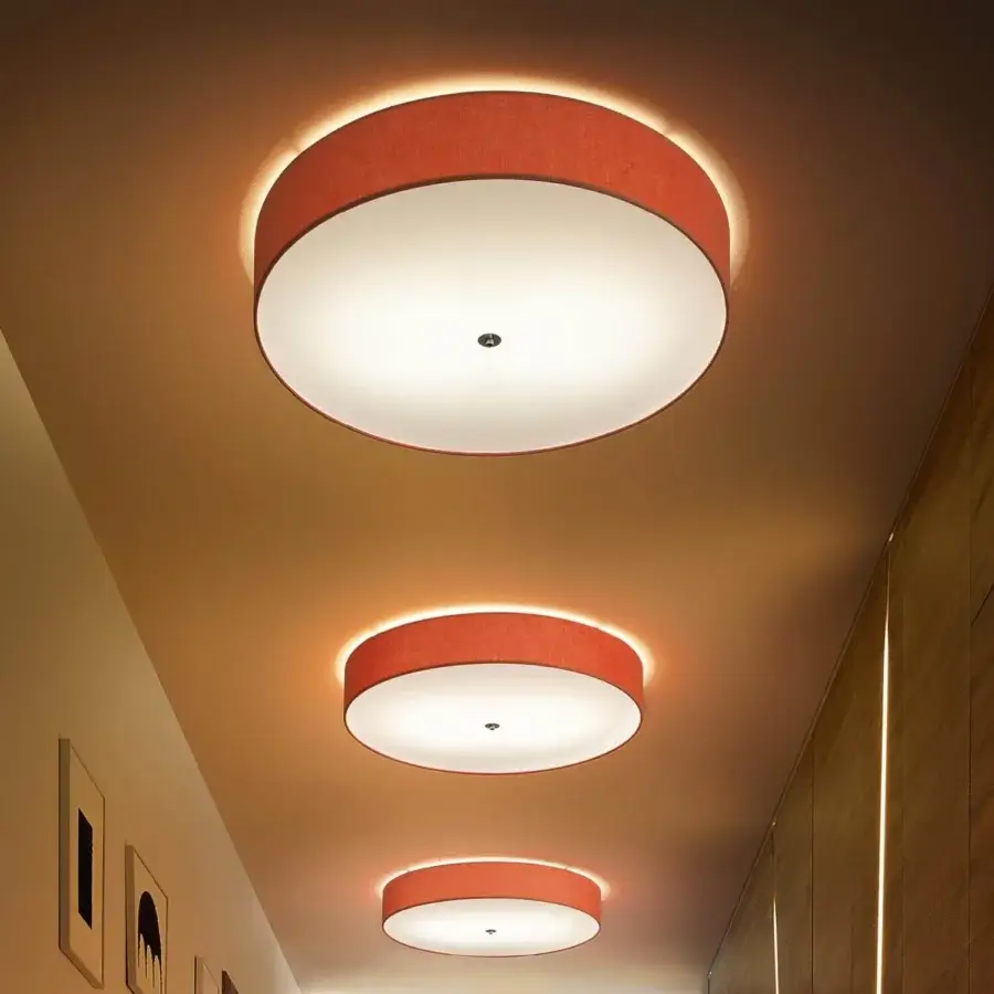Elegant Modo Luce Discovolante ceiling lamp with reddish-orange textile and matte white central disc creating a warm diffused glow