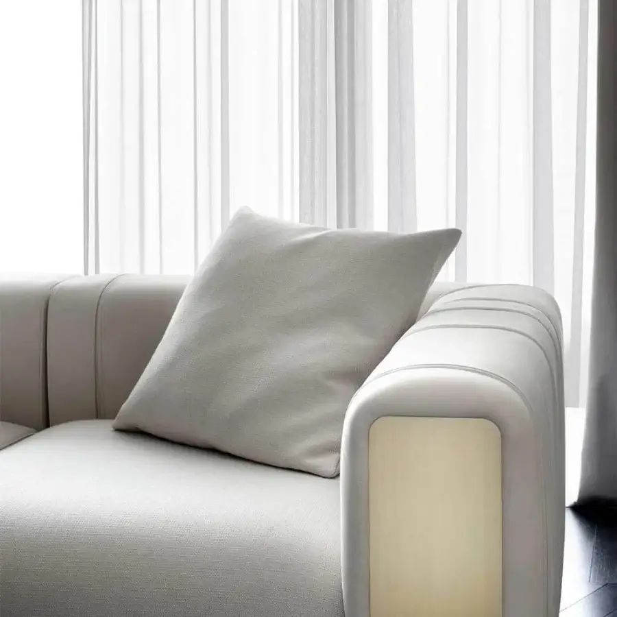 Elegant Rugiano Luz sofa upholstered in light gray textile with refined brushed brass detailing and wood inset panels