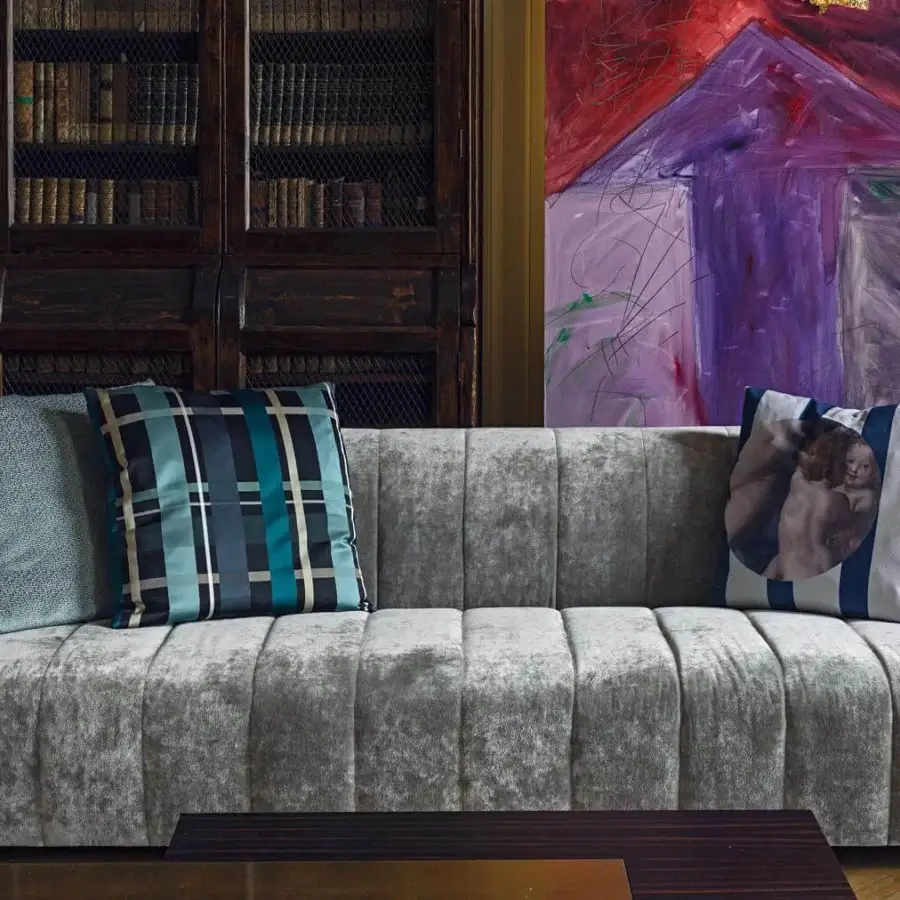 Elegant Erba Belladonna sofa with quilted detailing and soft padding upholstered in grey ribbed textile with light blue, plaid, and striped cushions