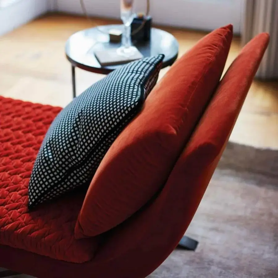 Distinctive OAK Vittoria chaise lounge upholstered in deep red-orange textile with quilted seating and black nickel metal base
