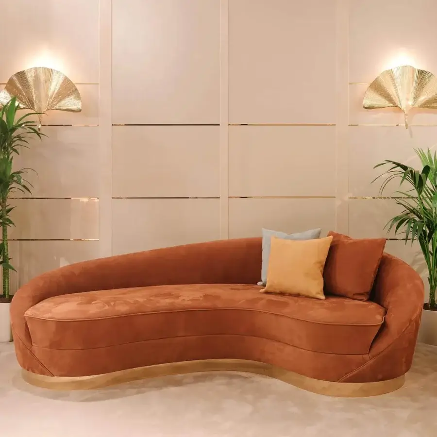 Superior Vismara Wavy sofa upholstered in rust-orange textile with a refined plated gold steel band base and pale pillows