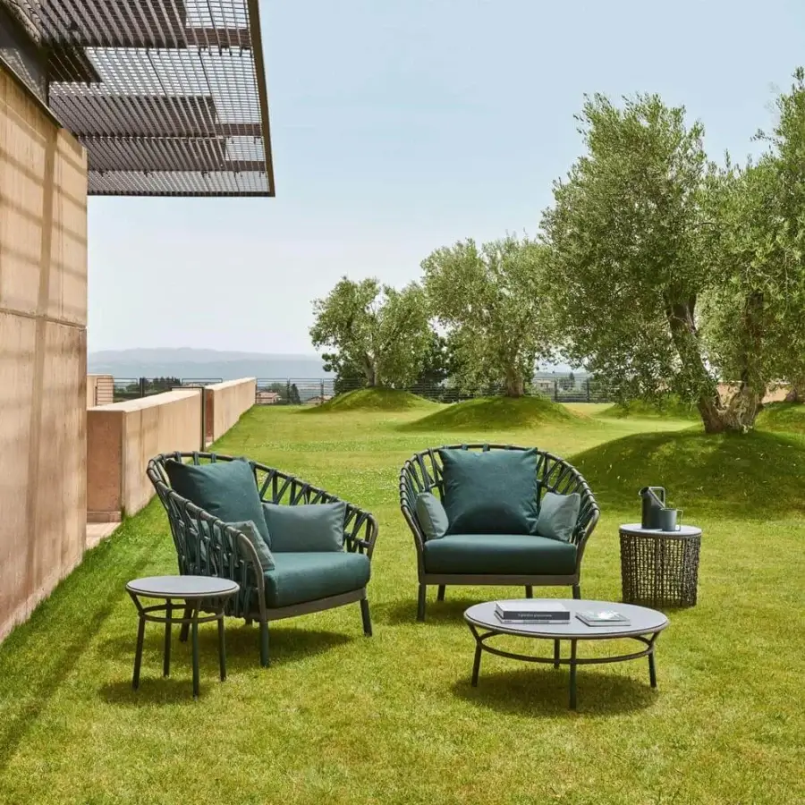 Elegant Varaschin Emma Cross lounge chair with deep teal cushions and woven dark metal with acrylic frame
