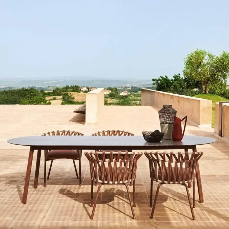 Sophisticated Varaschin Emma table with dark gray bush-hammered ceramic top and powder-coated aluminum frame built with tapered brown metal legs