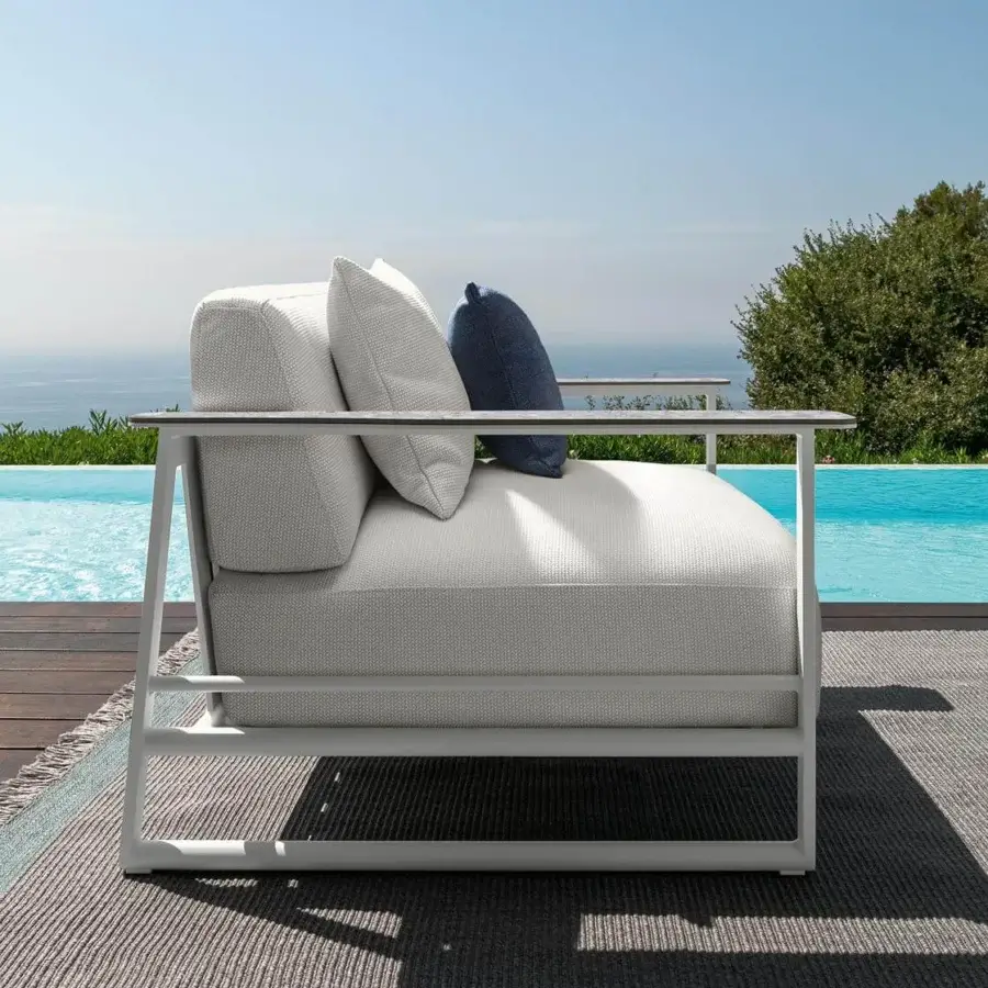 Exceptional Talenti Riviera sofa with geometric form, light gray weather-resistant cushions and dark blue accent pillow with stoneware armrests and matte aluminum finish