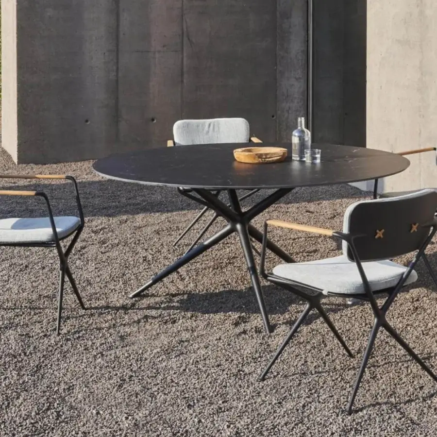 Elegant Royal Botania Exes table with dark matte ceramic top and intersecting coated aluminum base for outdoor settings