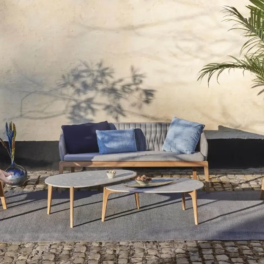 Elegant Royal Botania Calypso lounge chair with teak base, quilted light gray textile upholstery and stainless steel backrest