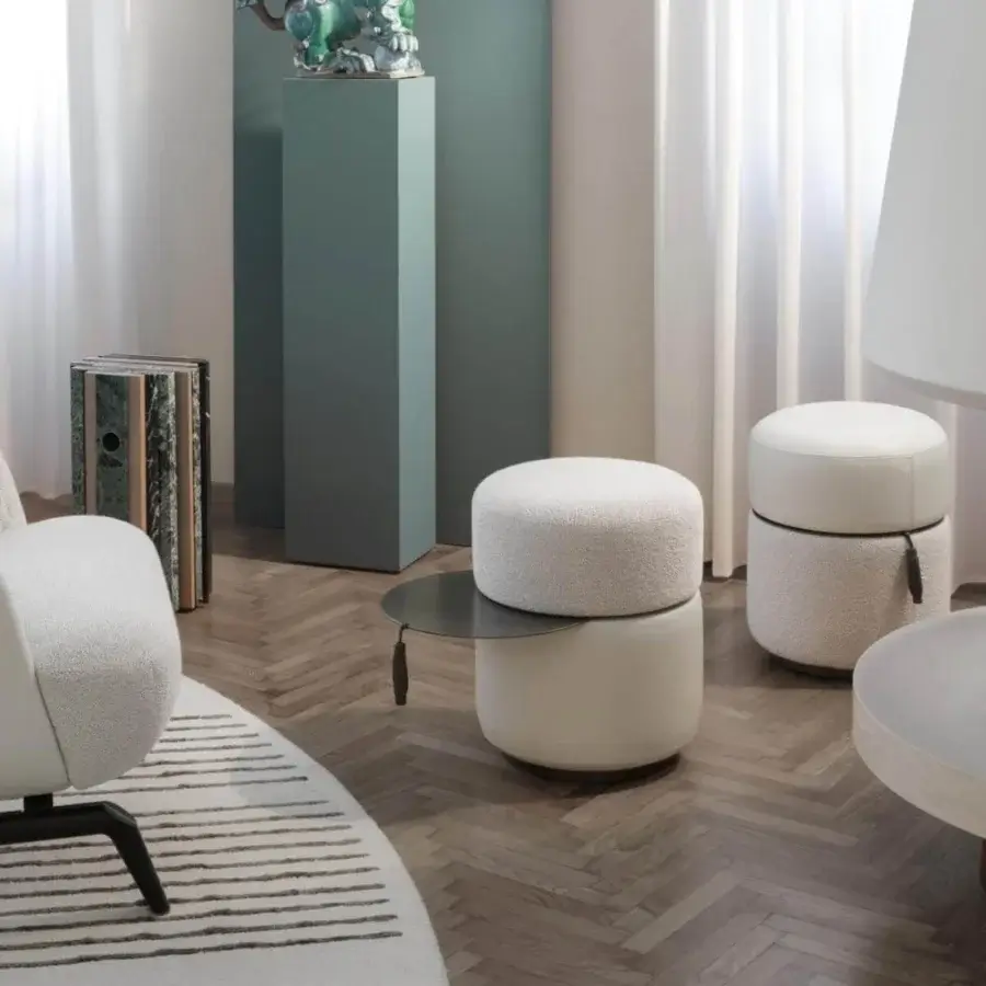 Exclusive Giorgetti Otto ottoman with creamy boucle-like fabric and dark gray swiveling steel, accented by a gray leather ribbon pull