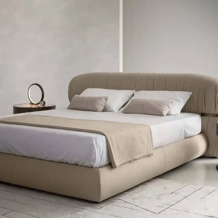 Elegant Rugiano Fandango bed with enveloping lines in smooth light beige leather and bronzed brass metal embellishment