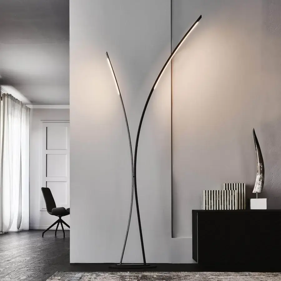 Curving dark structure rises beside a white architectural opening with fabric and a dark rug in the foreground