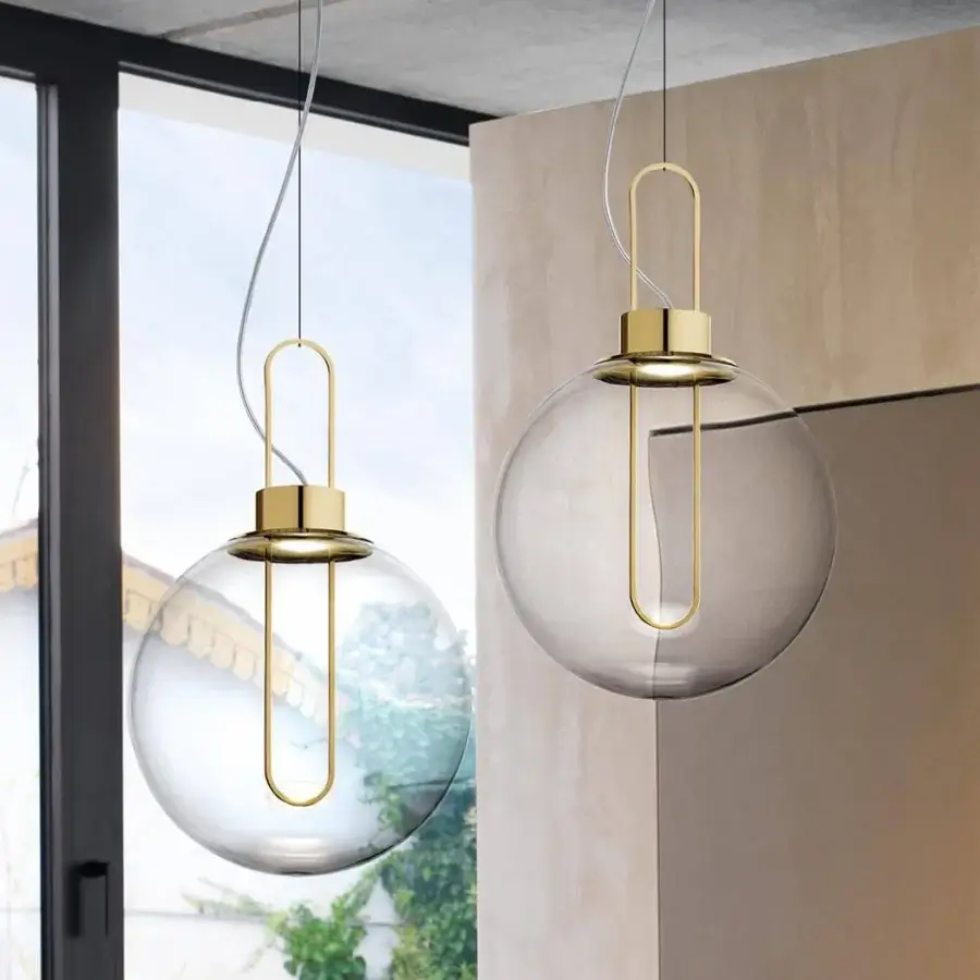 Elegant Modo Luce Orb suspension lamp with a clear PMMA diffuser and polished gold-toned metal frame
