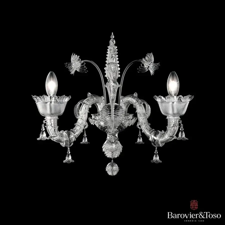Symmetrical glass fixture with branching supports, cup-shaped forms, and a central elongated element against a dark backdrop