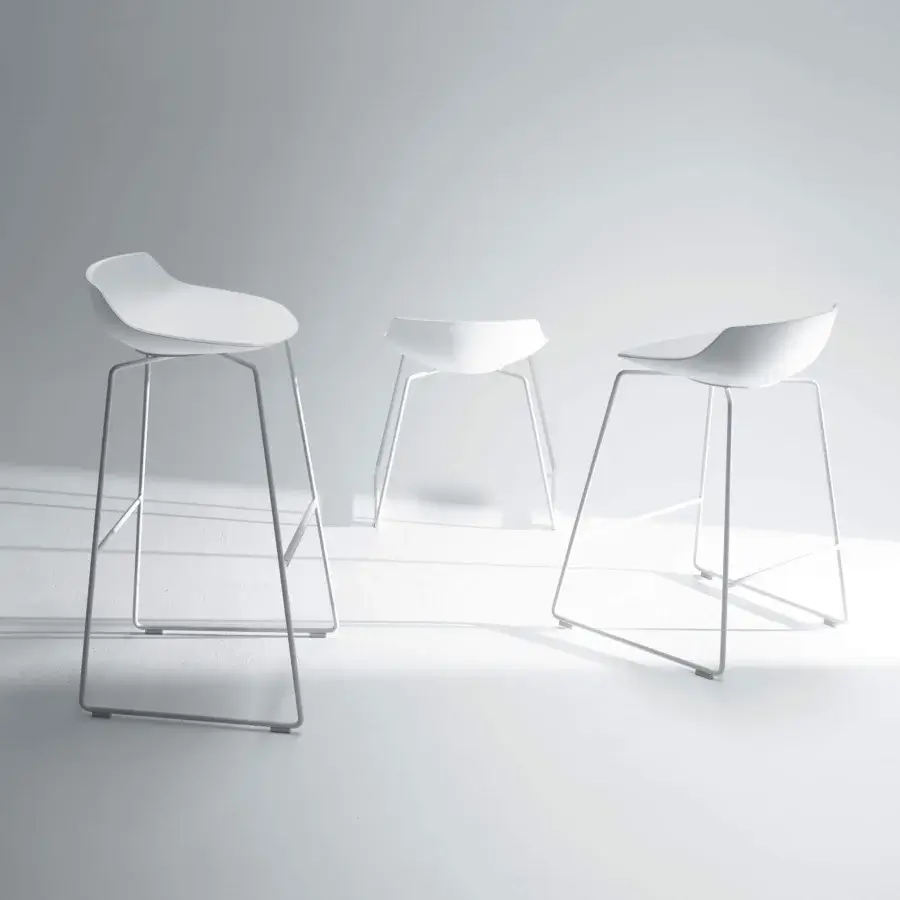 Pale molded forms with slender metal legs are arranged on a light gradient surface with soft shadows
