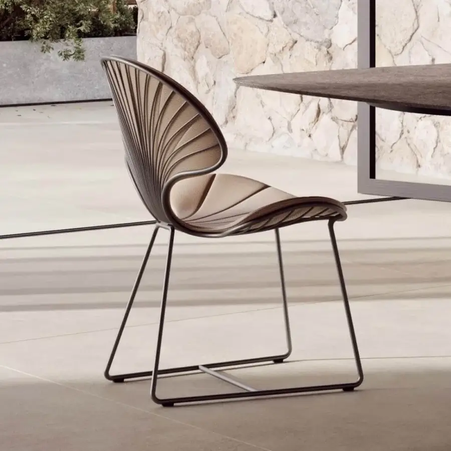 Luxury Royal Botania Ostrea chair with light beige textile seat and backrest contrasted by a dark metal frame, showcasing an oyster-inspired silhouette