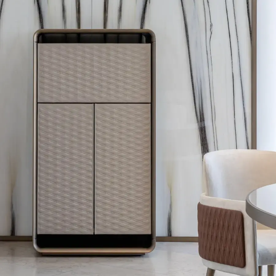 Distinguished Reflex Oh cupboard with rounded wood structure and bronze finish, showcasing light beige leather doors with diamond quilting