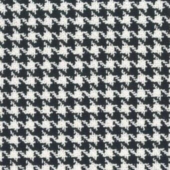 Houndstooth textile sample in black and off-white with interlocking diamond shapes, dense repeating motif on charcoal gray, Mariani fabric.