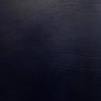 Vegetable-tanned saddle leather texture in dark blue, displaying a mottled surface with irregular grain and matte finish.