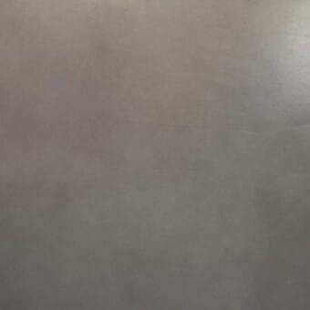 Vegetable-tanned saddle leather, grayish-brown tone, textured surface, matte finish, natural grain, uniform color, minimal imperfections visible.