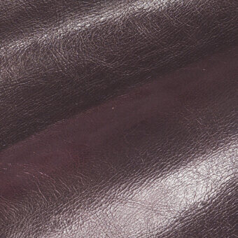 Saddle leather texture in melanzana purple displays a pronounced grain, fine wrinkles, and a subtly glossy finish with tonal variations.