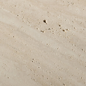 Honed travertine marble texture displaying light beige tones, porous surface with irregular pits, matte finish, natural stone material.