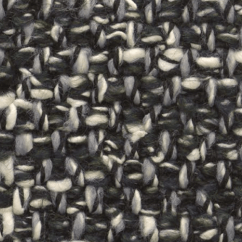 Woven tweed-like fabric texture with dense black and off-white yarns, exhibiting a loose plain weave and nubby, grayscale surface.