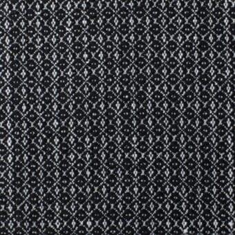 Boucle fabric sample with black and off-white geometric pattern; interlocking diamonds and crosses create a dense, textured surface.