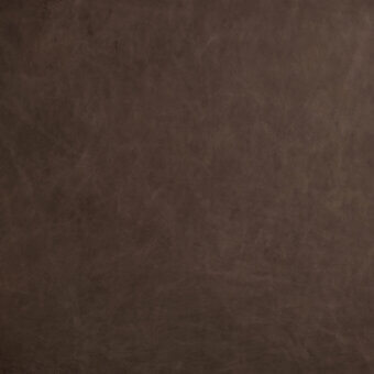 Distressed leather texture in dark cognac, exhibiting mottled markings and faint scratches, with overlaid text identifying brand and color.