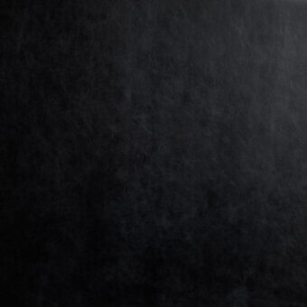 Black leather texture with mottled grain and tonal variations, displaying subtle gray highlights and a diffused, natural finish.