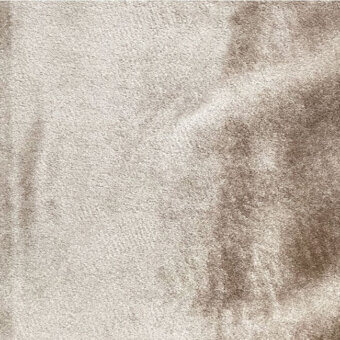 Pile velvet fabric in beige and taupe tones displays a dense, short-pile texture with subtle directional nap and mottled, organic color variations.
