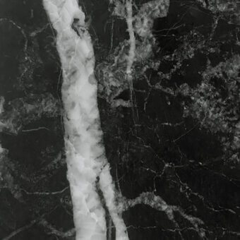 Matt statuario black marble texture with irregular white and light gray veins, displaying a subtle grainy surface and vertical streaks.
