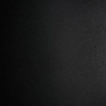 Black embossed metal texture with matte finish, uniform dark tone, and subtle granular appearance, featuring soft diffused lighting.