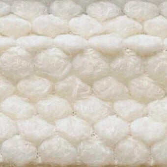 Clear plastic textile sample with repeating hexagonal air pockets, creating a cushioned cellular texture and subtle sheen, labeled “egoitaliano puffo 101”.