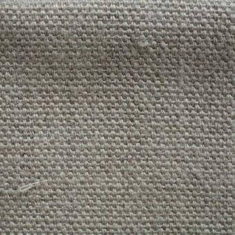 Linen fabric sample, gray-beige tone, dense square weave with stone-washed texture and visible fibers; label reads “erba lino stone washed 018”.