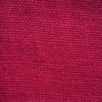 Red lino stone washed fabric texture displaying a dense, nubby weave with dye variations, erba fabrics collection 33.