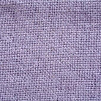 Lavender linen fabric texture with a stone-washed finish and visible weave, displaying a heathered effect and printed label detail.