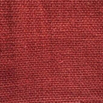 Stone washed linen fabric texture in terracotta, displaying a tight weave and granular surface with subtle tonal shifts and matte finish.