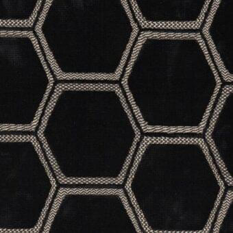 Geometric fabric sample, black hexagons with textured light beige thread outlines, dense repeating pattern, Erba brand "manipur noir" textile.