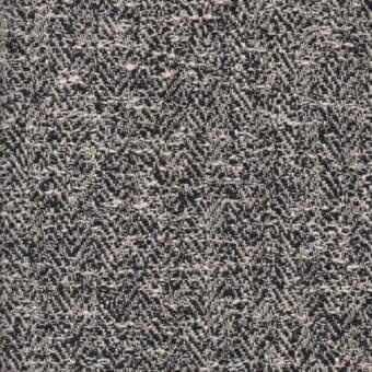 Grayscale fabric sample displaying a dense, irregular weave with dark charcoal and light gray flecks creating a speckled, textured surface.