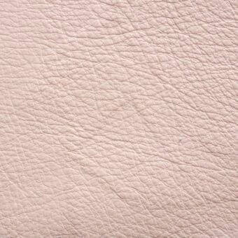 Pale pink leather texture with a dense, irregular grain and matte finish, displaying subtle tonal variations and a supple appearance.