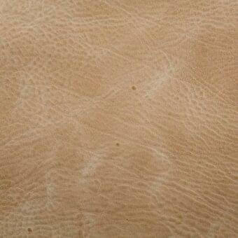 Zebu rye leather texture displaying a tan color with natural grain, creases, and circular markings against a neutral backdrop.